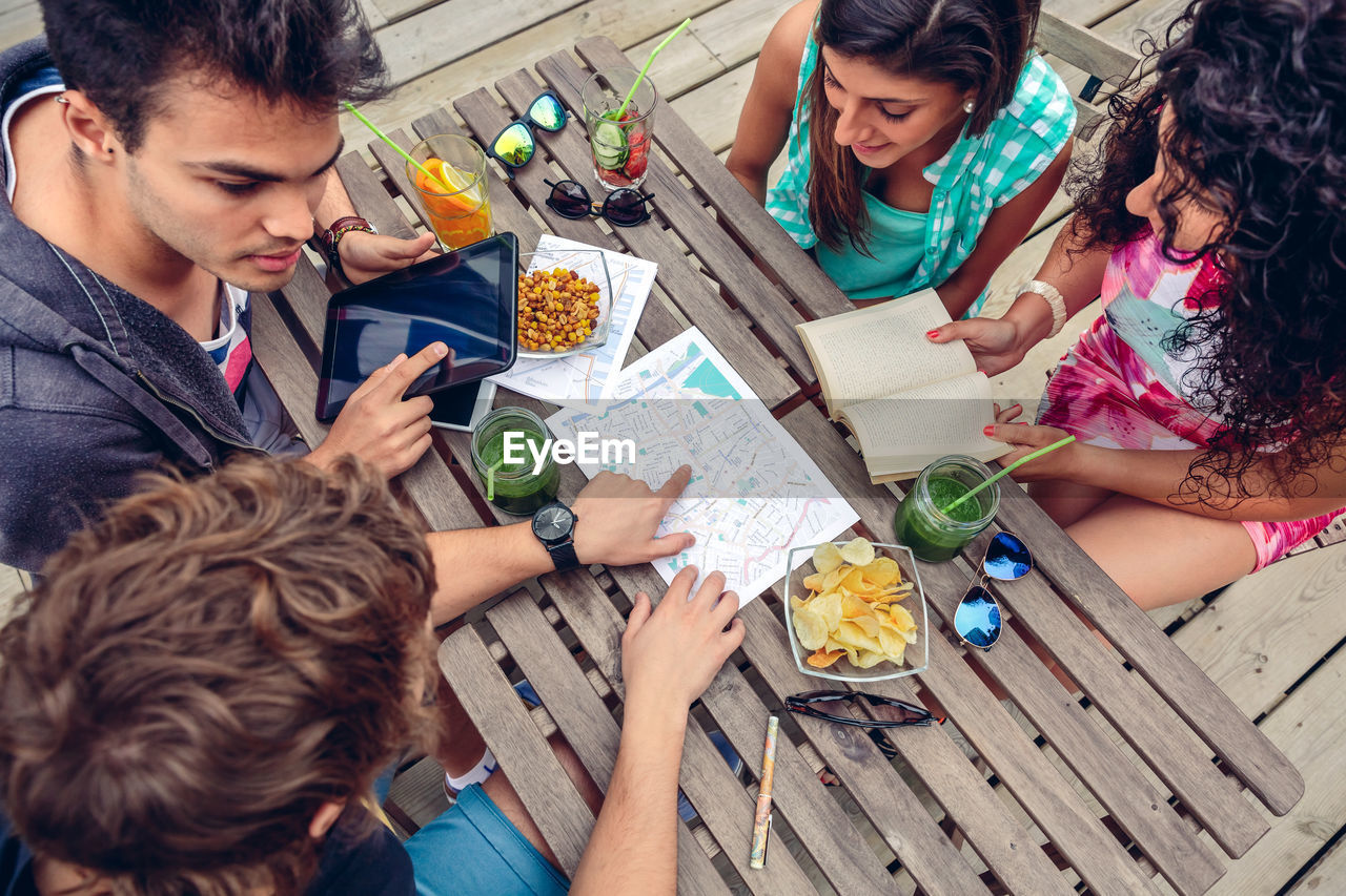 High angle view of friends looking at map while sitting in restaurant