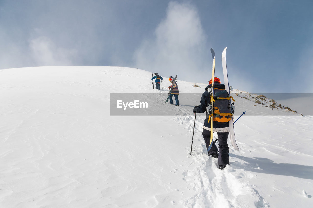 Backcountry climbers, ski climber, walking with skis and snowboard in the mountains. 