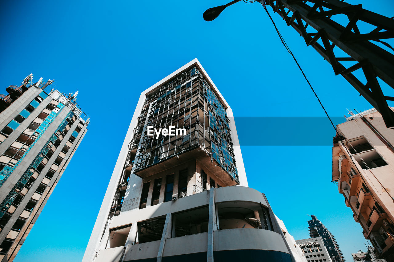 Low angle view of damaged buildings against clear blue sky