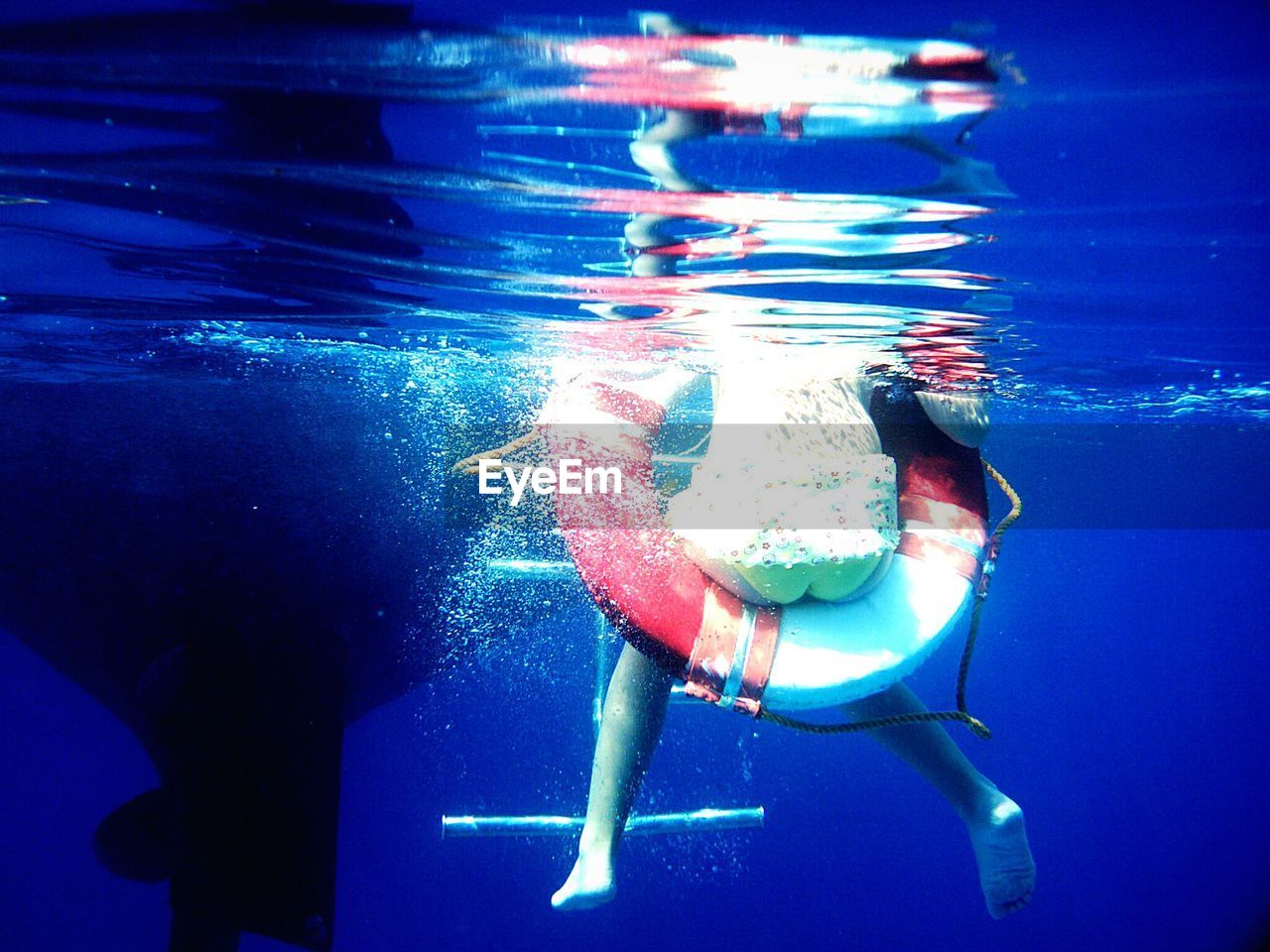 Boy sitting on life belt in blue sea