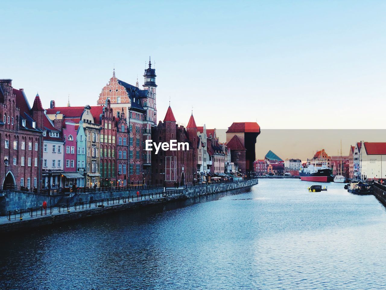 View of buildings by river against clear sky