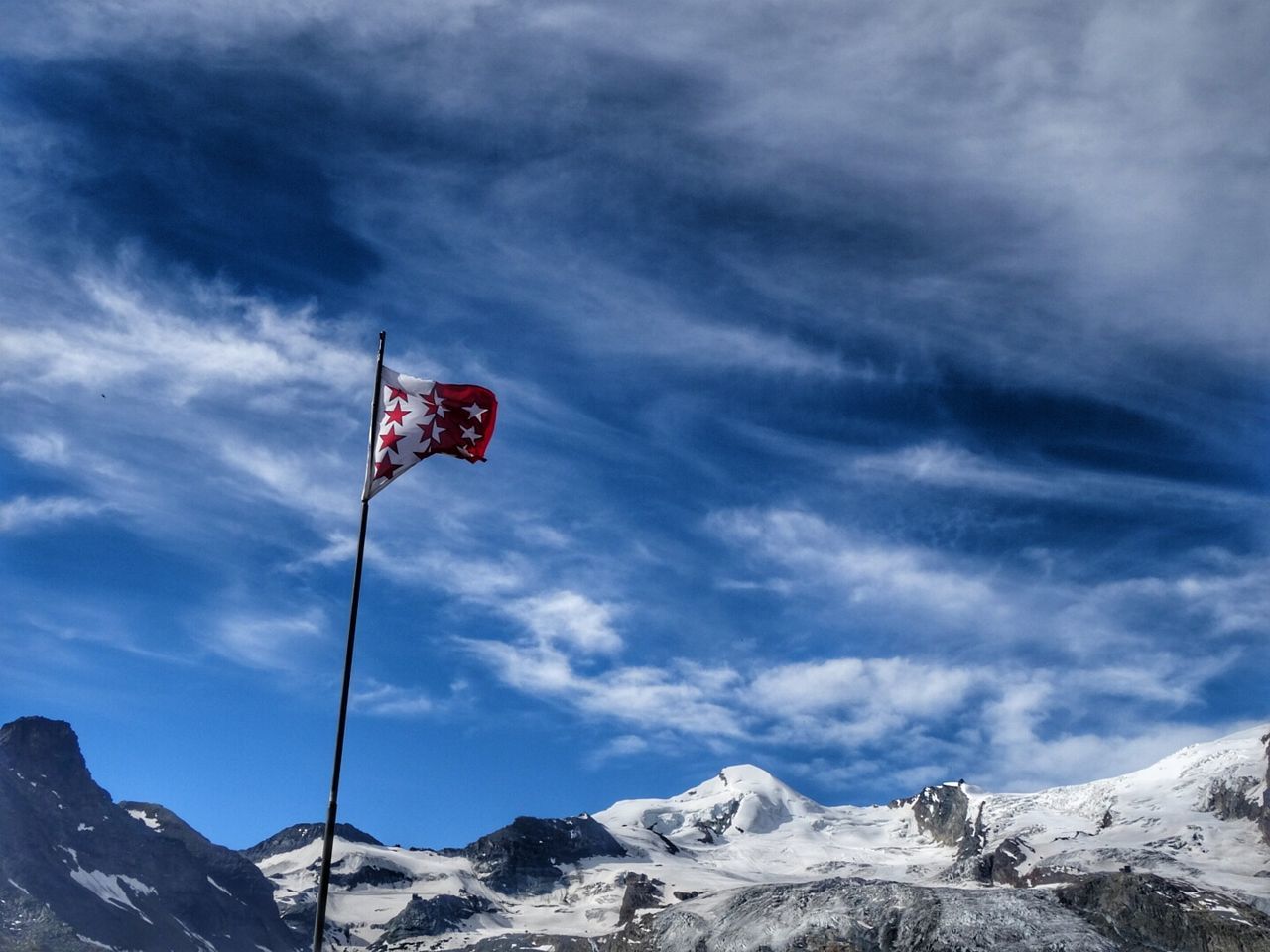 LOW ANGLE VIEW OF FLAG ON SNOW COVERED MOUNTAIN AGAINST SKY