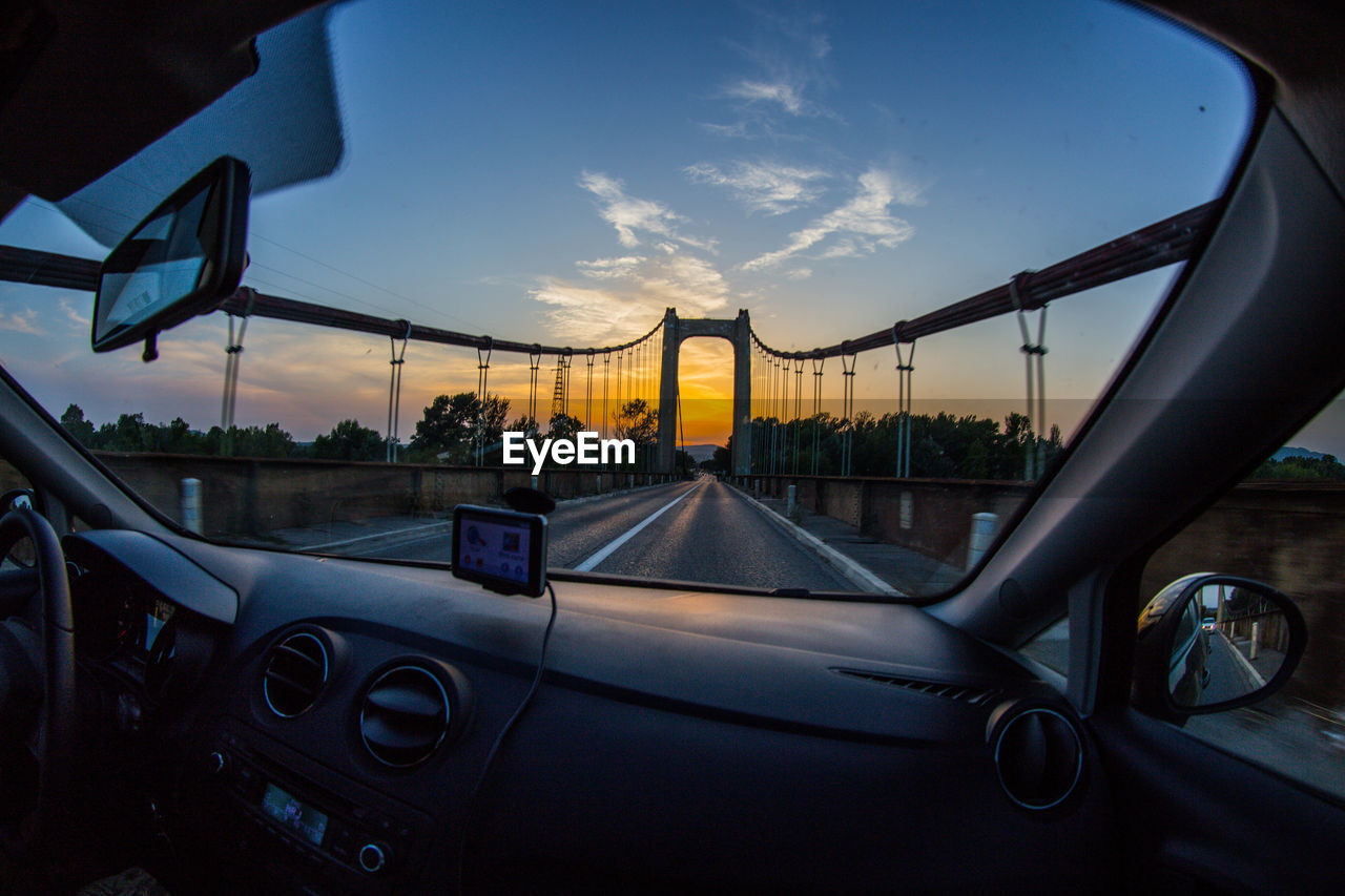 Cars on bridge against sky during sunset
