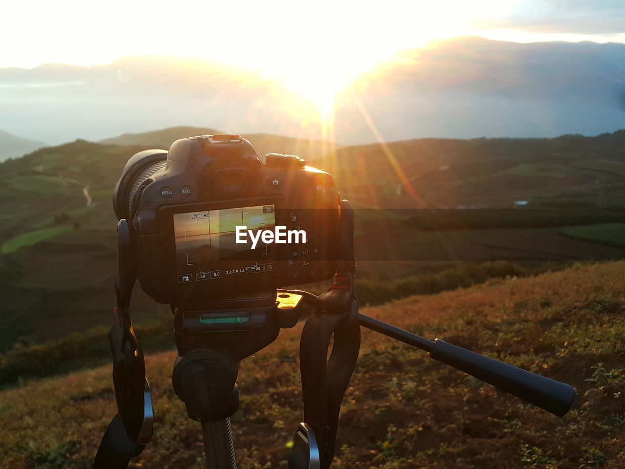 CAMERA PHOTOGRAPHING ON LANDSCAPE AGAINST MOUNTAINS