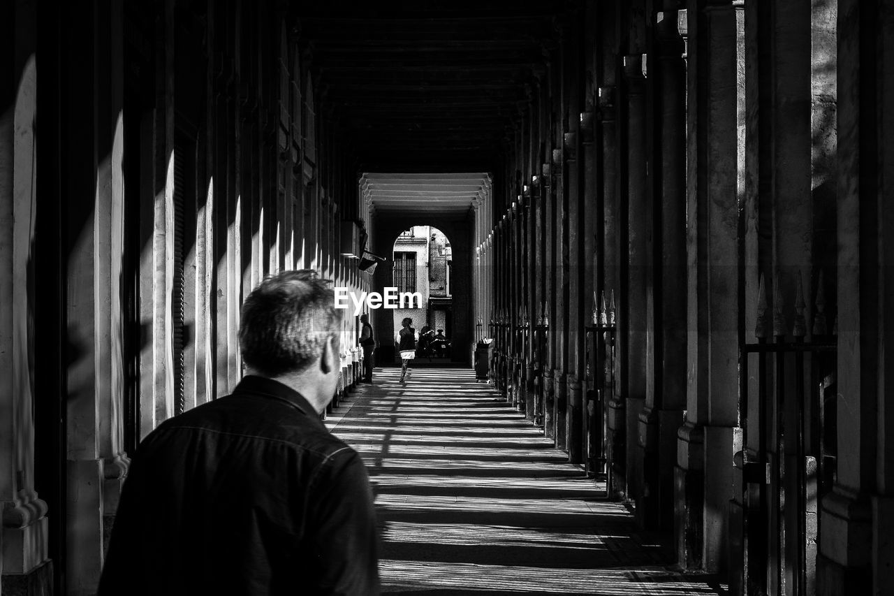 MAN STANDING IN CORRIDOR OF CATHEDRAL