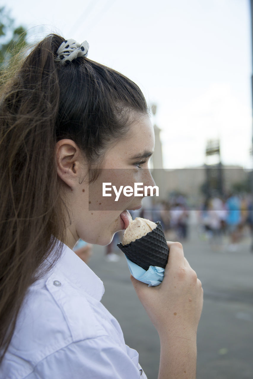 Side view of young woman licking ice cream