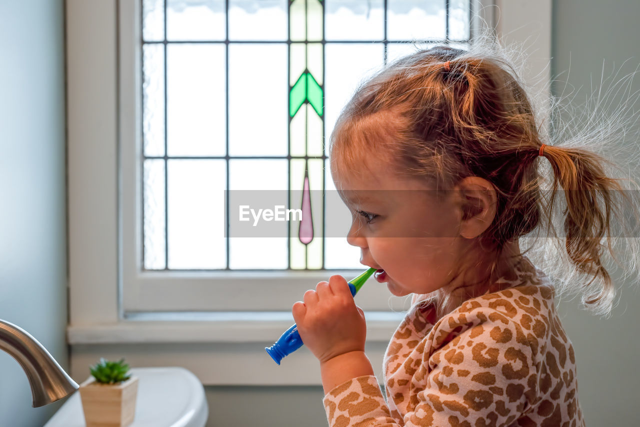 Cute girl brushing teeth at home