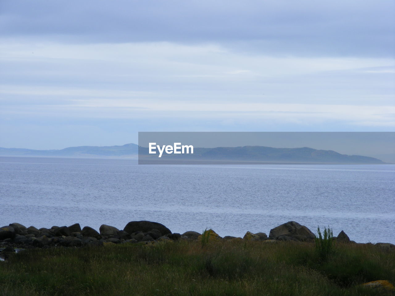 SCENIC VIEW OF SEA WITH MOUNTAIN RANGE IN BACKGROUND