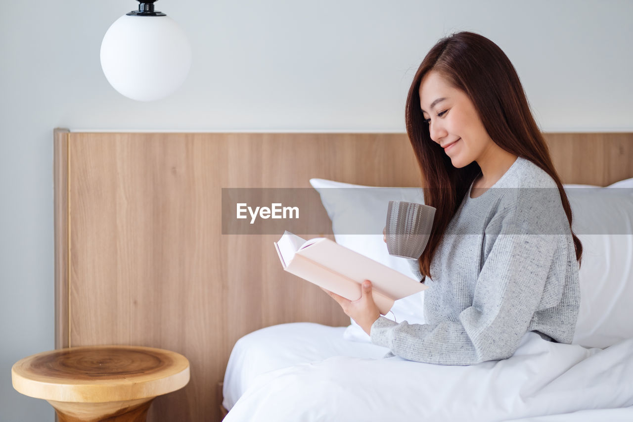 Smiling woman reading book at home