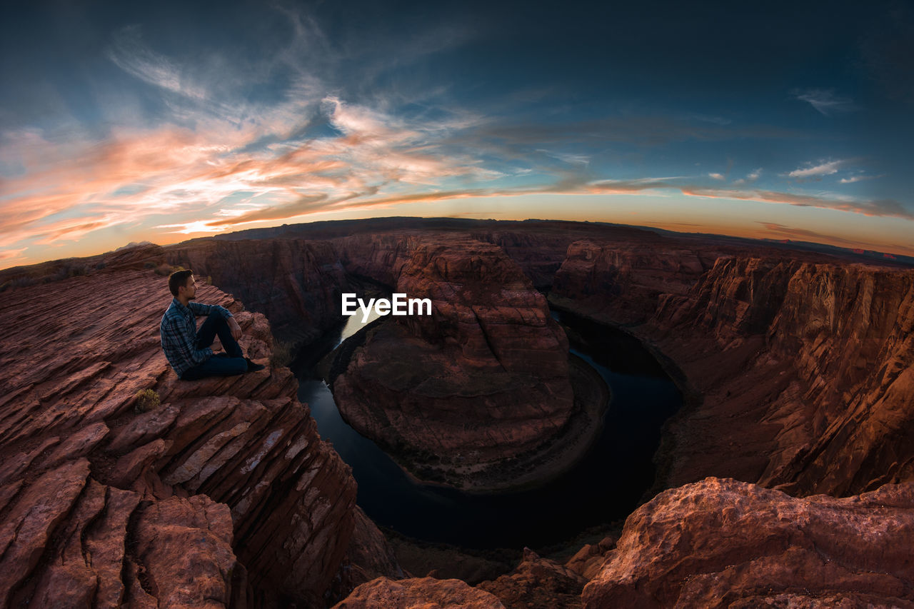 Hiker sitting on rock formation horseshoe bend