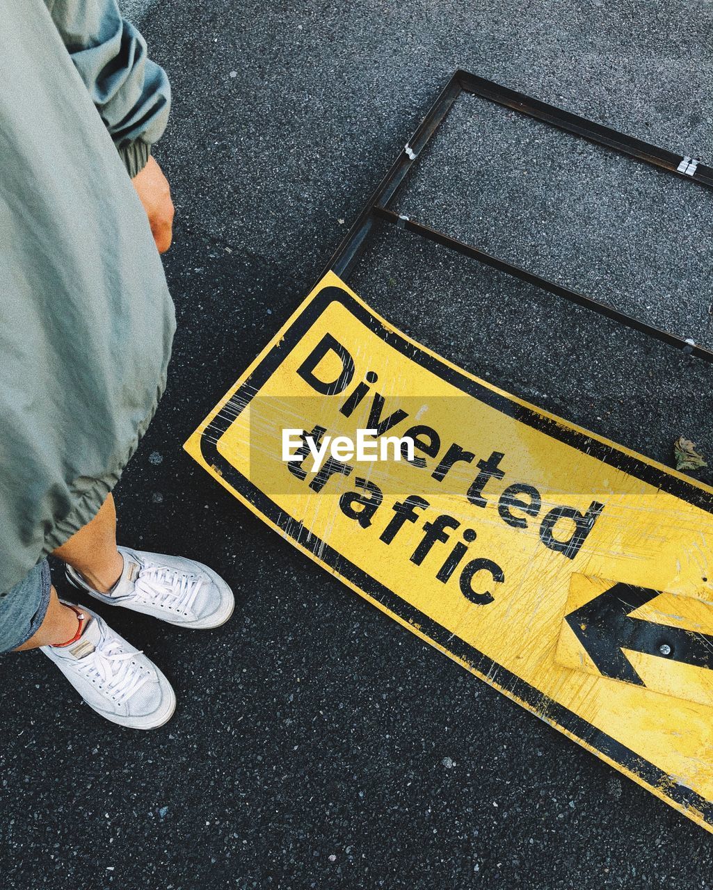 Low section of woman standing by information sign on road