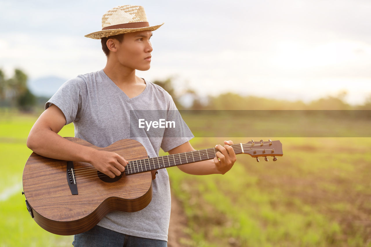 YOUNG MAN PLAYING GUITAR ON A HAND