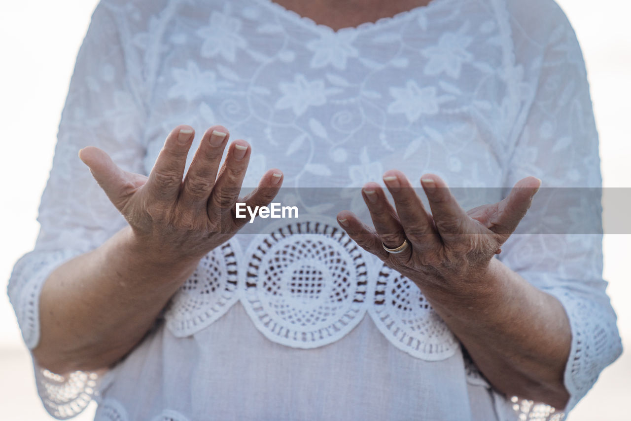 hand, midsection, one person, adult, clothing, front view, arm, pattern, sleeve, t-shirt, studio shot, textile, indoors, finger, person, religion, holding, men, close-up