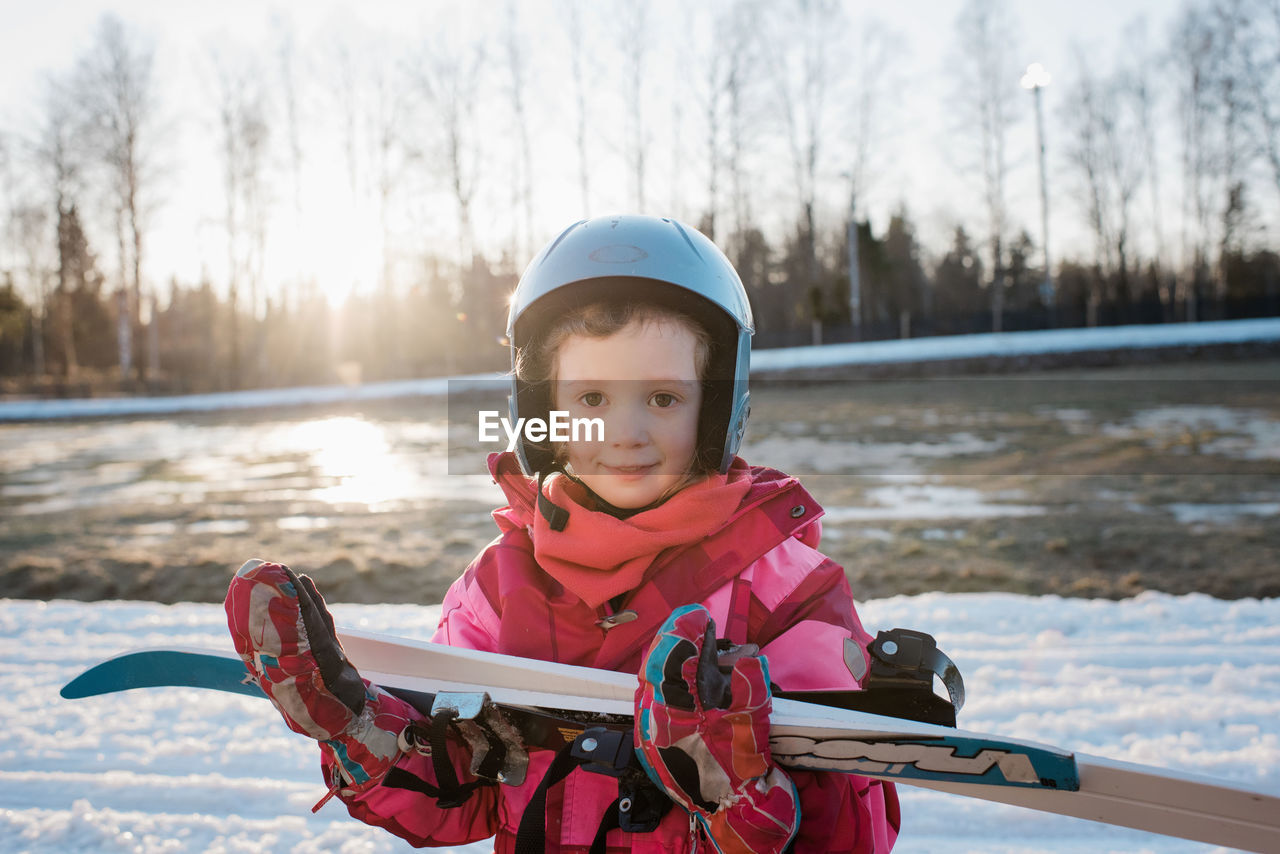 Portrait of a young girl holding her cross country skis at sunset
