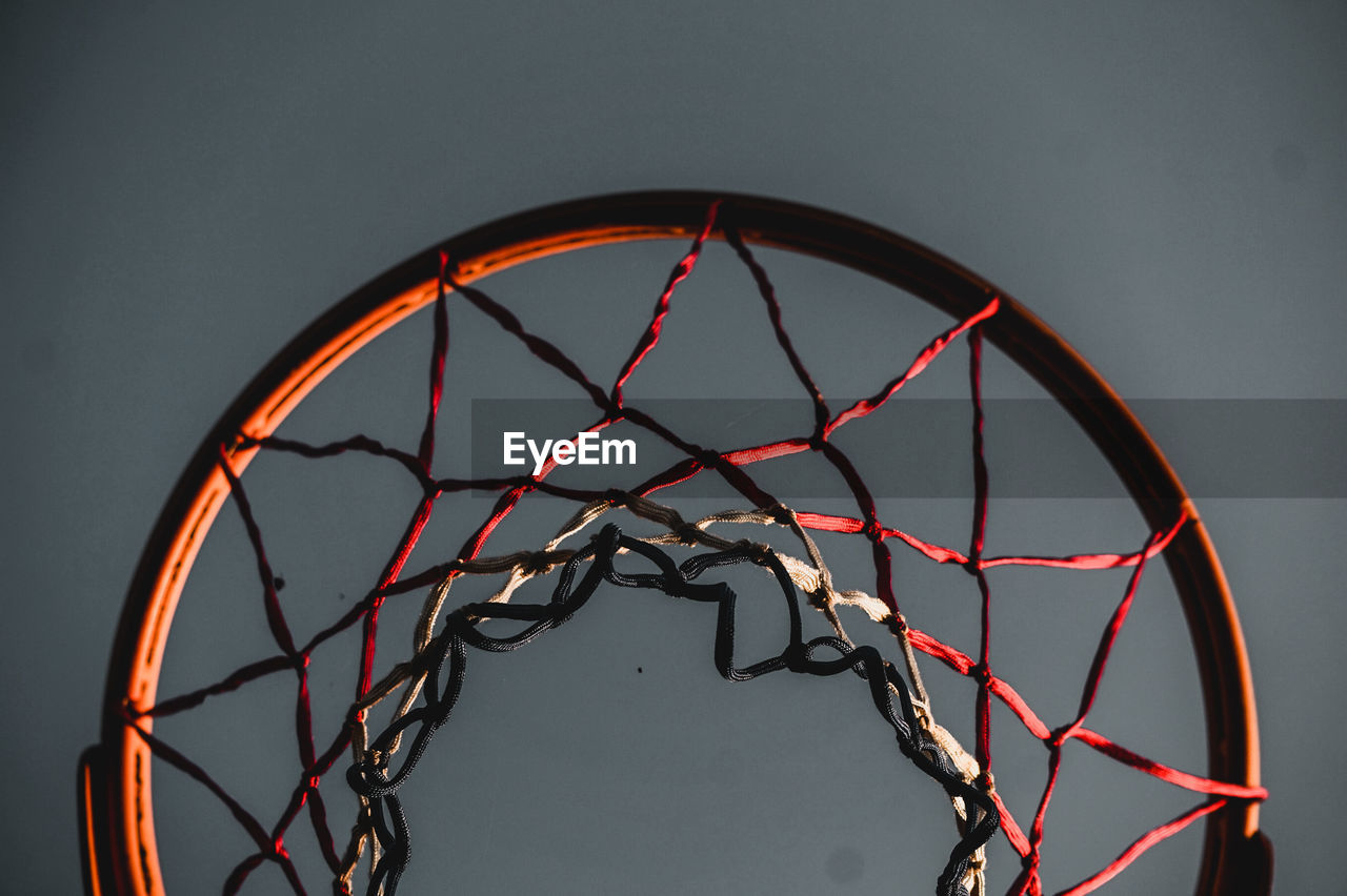 LOW ANGLE VIEW OF BASKETBALL HOOP AGAINST SKY SEEN THROUGH METALLIC STRUCTURE