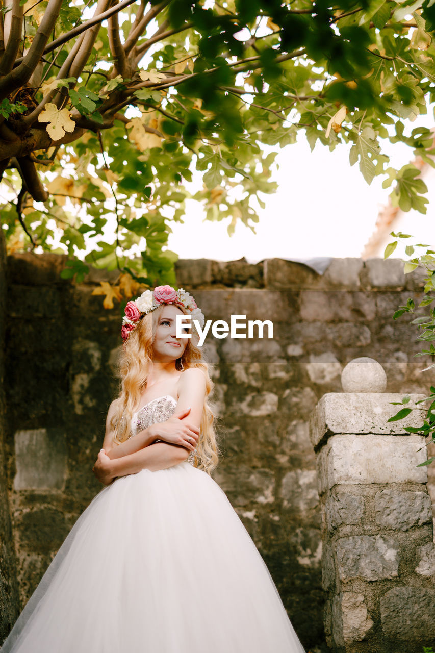 Bride looking away while standing against wall