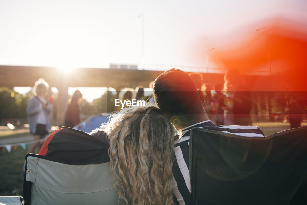 Rear view of loving couple enjoying in music festival against sky