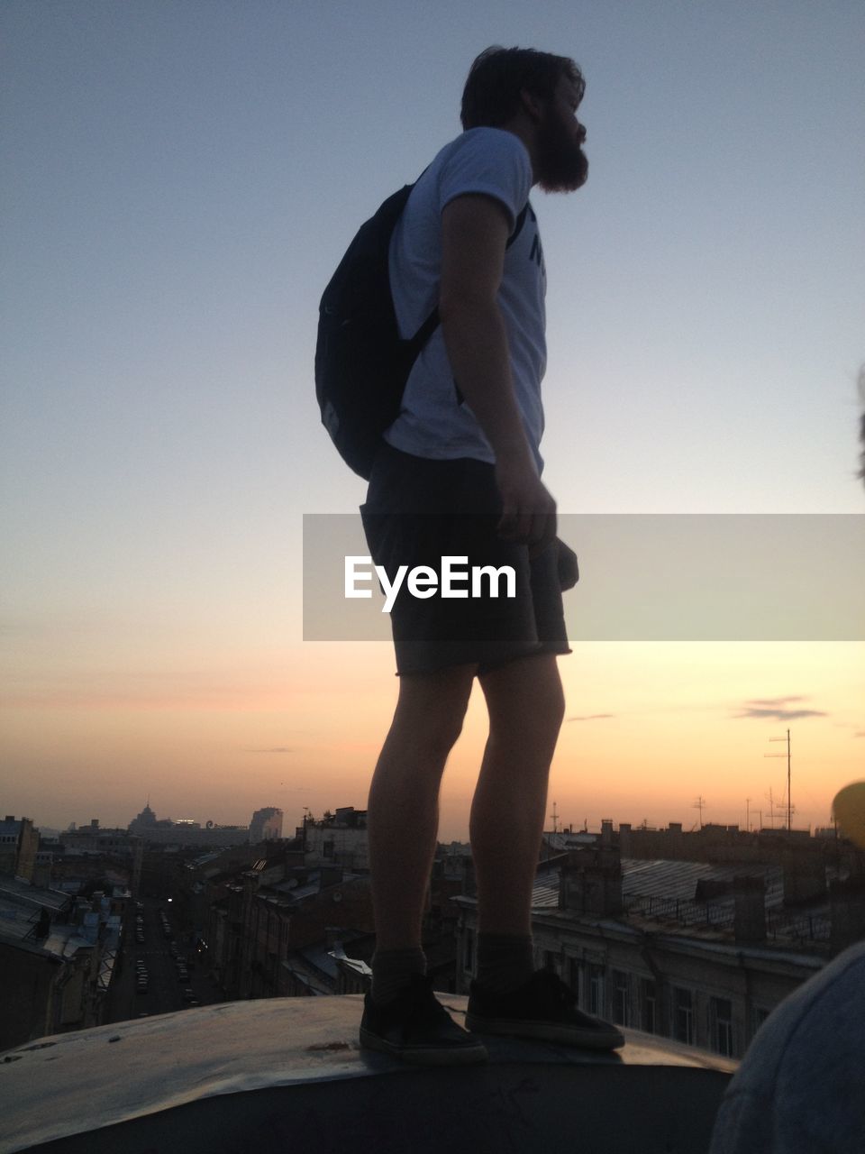 WOMAN STANDING BY RAILING AT SUNSET