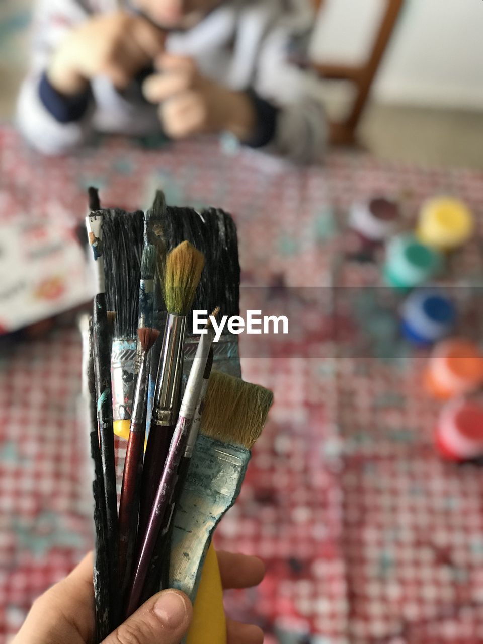 Close-up of hand holding paintbrushes
