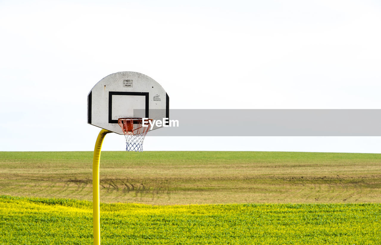 BASKETBALL HOOP ON FIELD AGAINST SKY