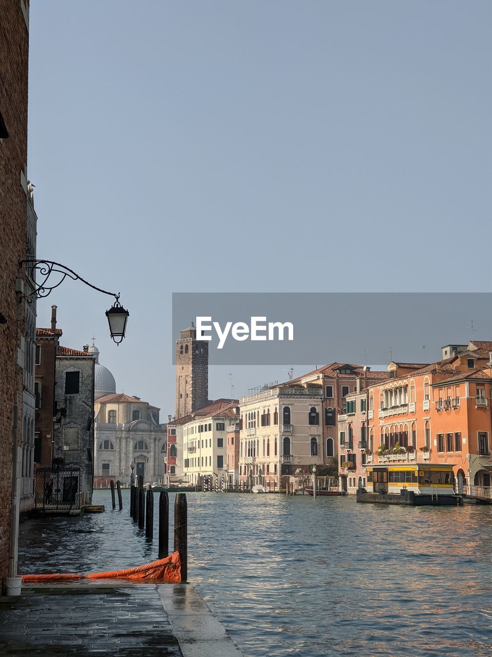 Canal amidst buildings against clear sky