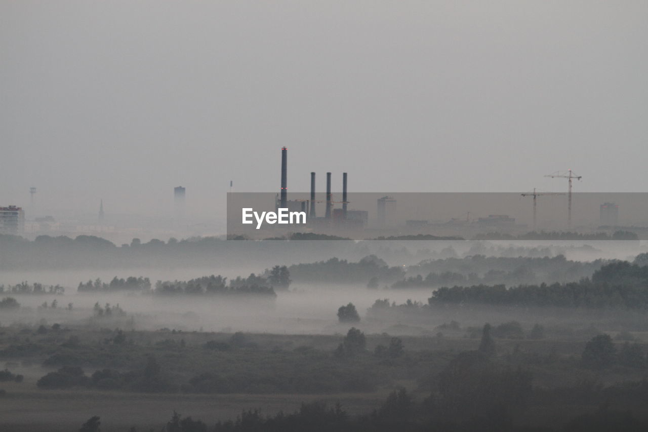 Smoke stack on landscape against sky