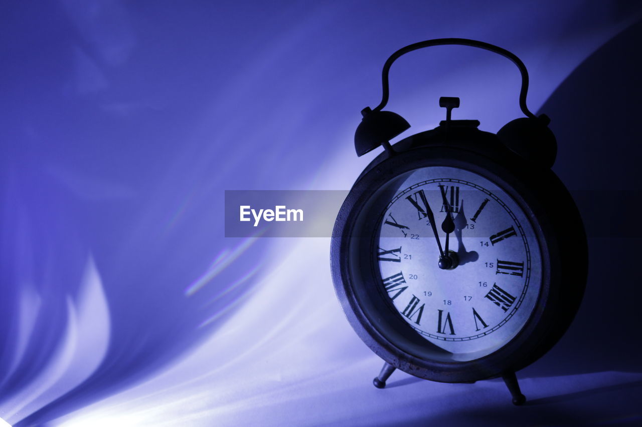 Close-up of alarm clock against wall