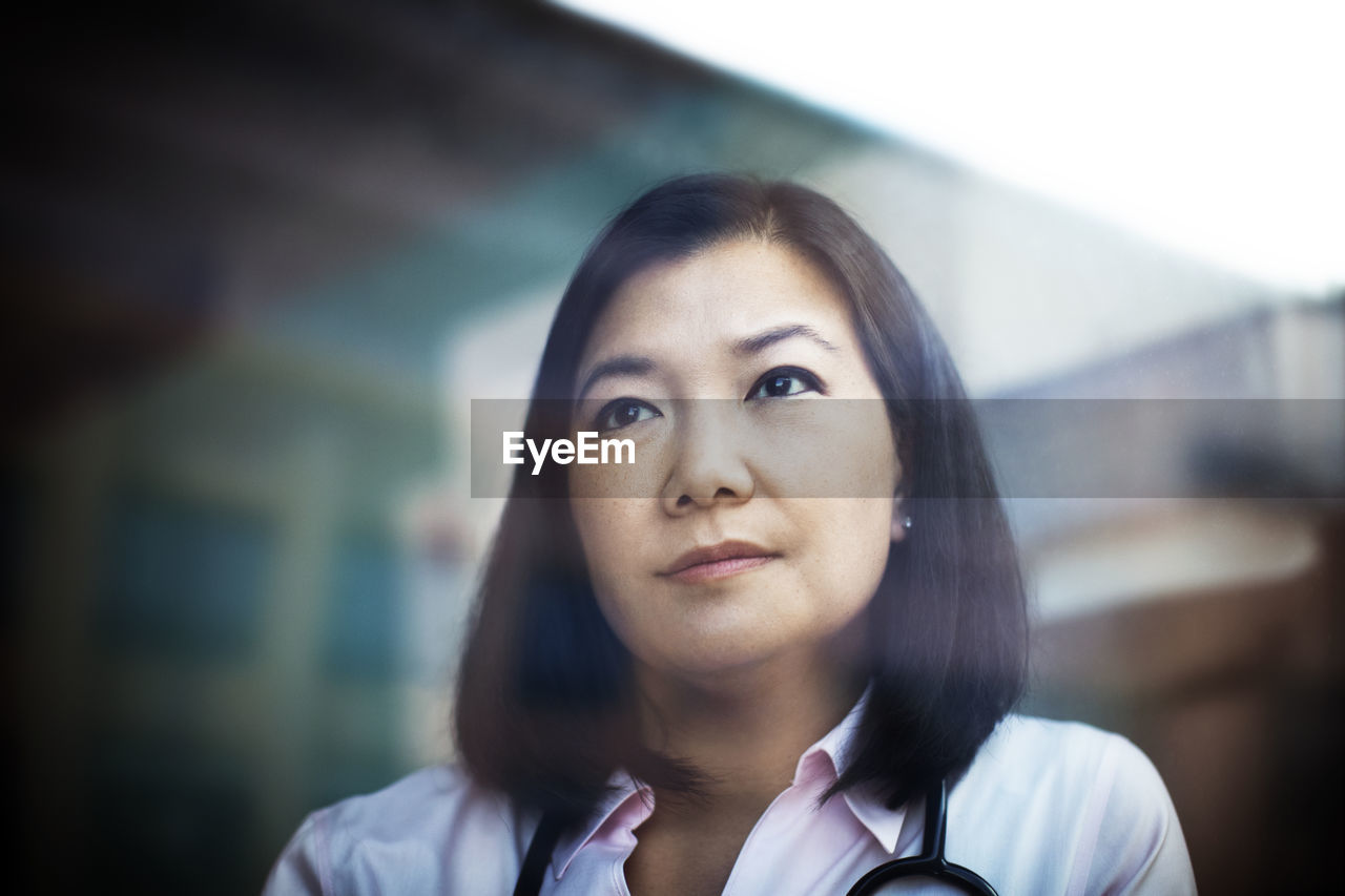 Thoughtful female doctor looking through window