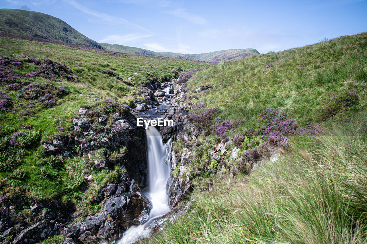 SCENIC VIEW OF WATERFALL ON MOUNTAIN