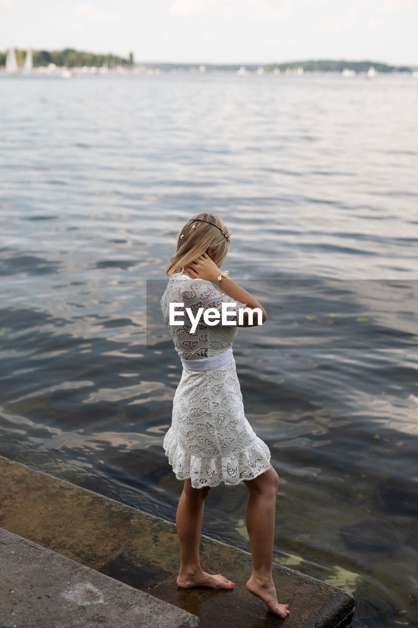 REAR VIEW OF WOMAN STANDING IN RIVER