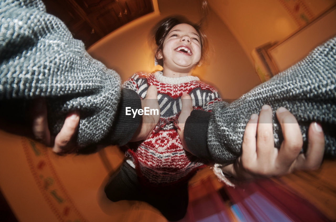 Cropped hands of mother carrying happy daughter in tunnel slide