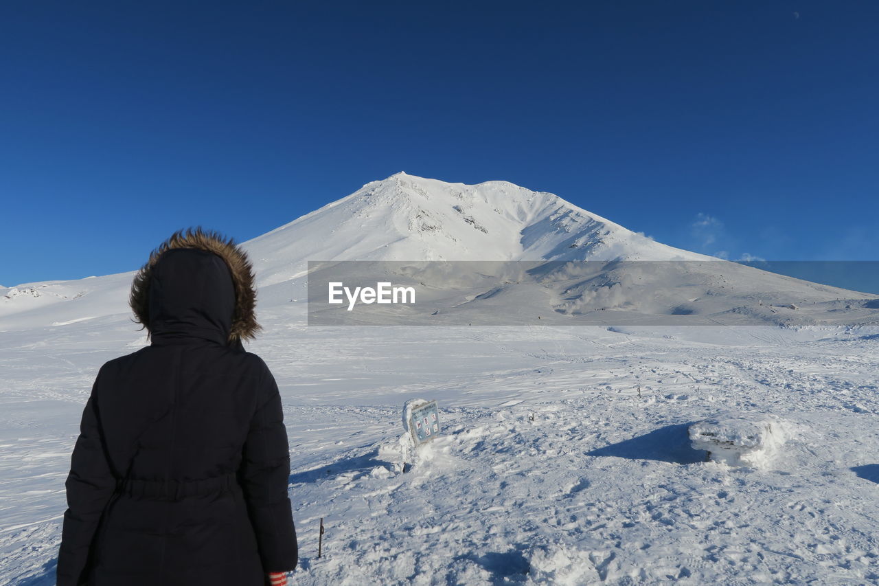 Rear view of woman on snowcapped mountain against sky