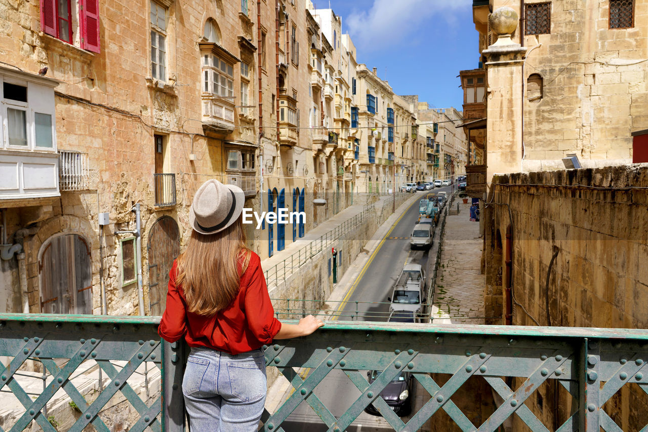 Traveler girl on iron bridge looking historic buildings in city centre of valletta, malta