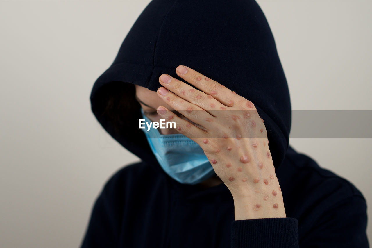 one person, clothing, studio shot, adult, indoors, portrait, obscured face, hand, headshot, person, black, covering, arm, emotion, men, sadness, front view, hiding