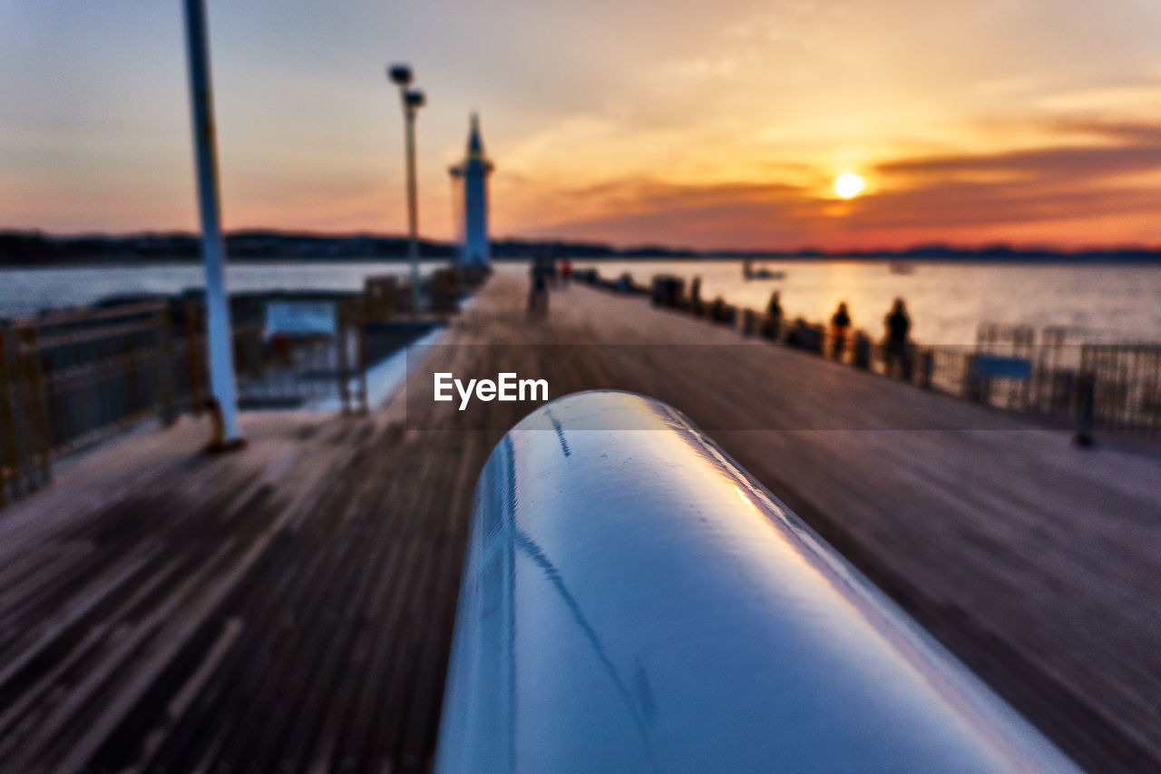 Scenic view of sea and pier against moody sky during sunrise