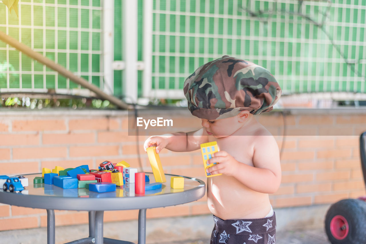 FULL LENGTH OF SHIRTLESS BOY LOOKING AT FARM