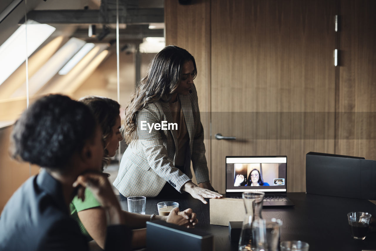 Female entrepreneur on video call through laptop with businesswomen at office