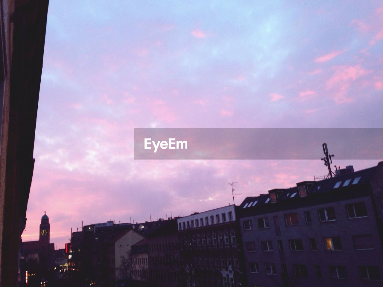 LOW ANGLE VIEW OF BUILDINGS AGAINST CLOUDY SKY AT SUNSET