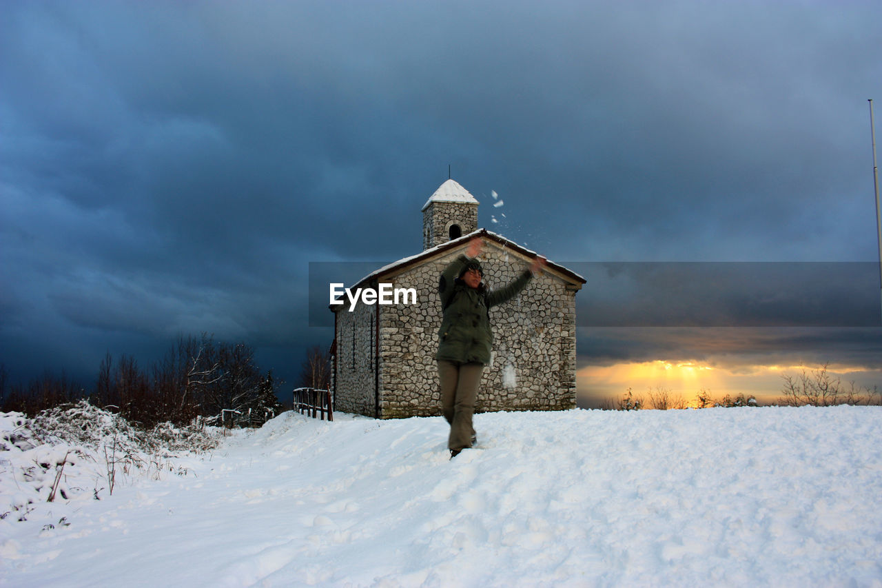 HOUSE ON SNOW COVERED FIELD AGAINST SKY