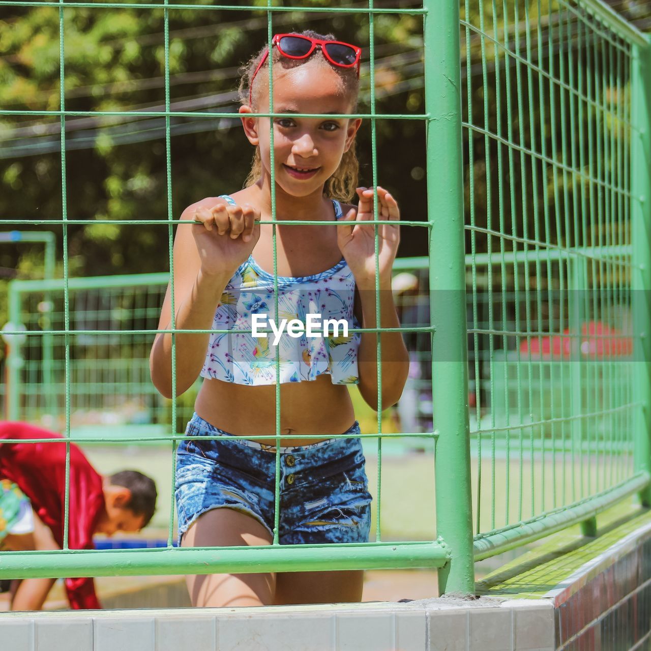 Portrait of smiling young woman looking through fence