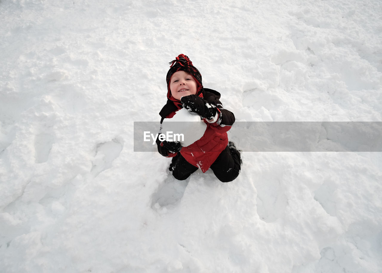 High angle view of cute boy playing in snow during winter