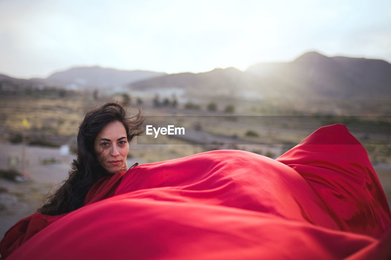 Portrait of woman in red dress against sky