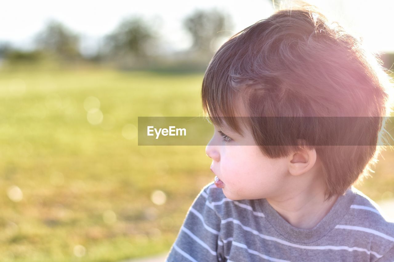 Close-up of cute boy looking away on field