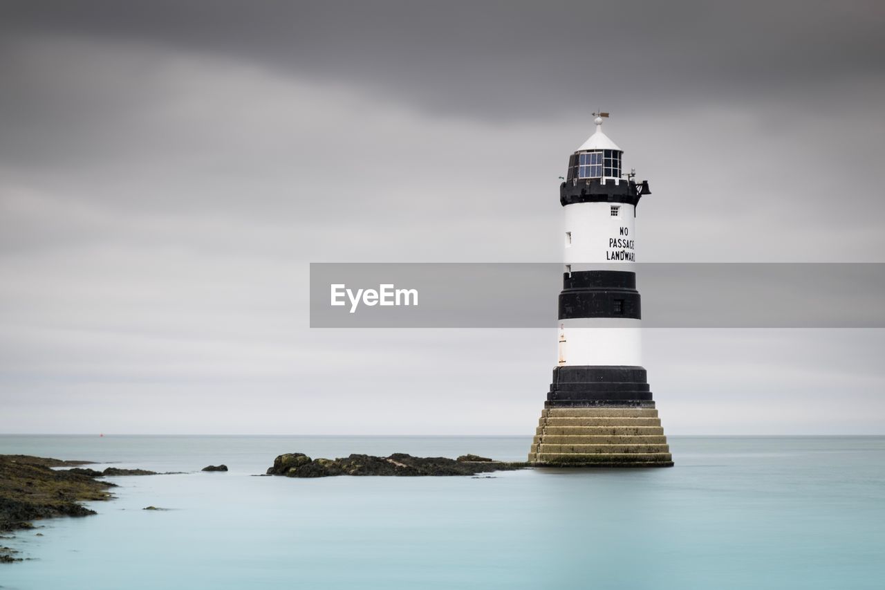 Lighthouse by sea against sky