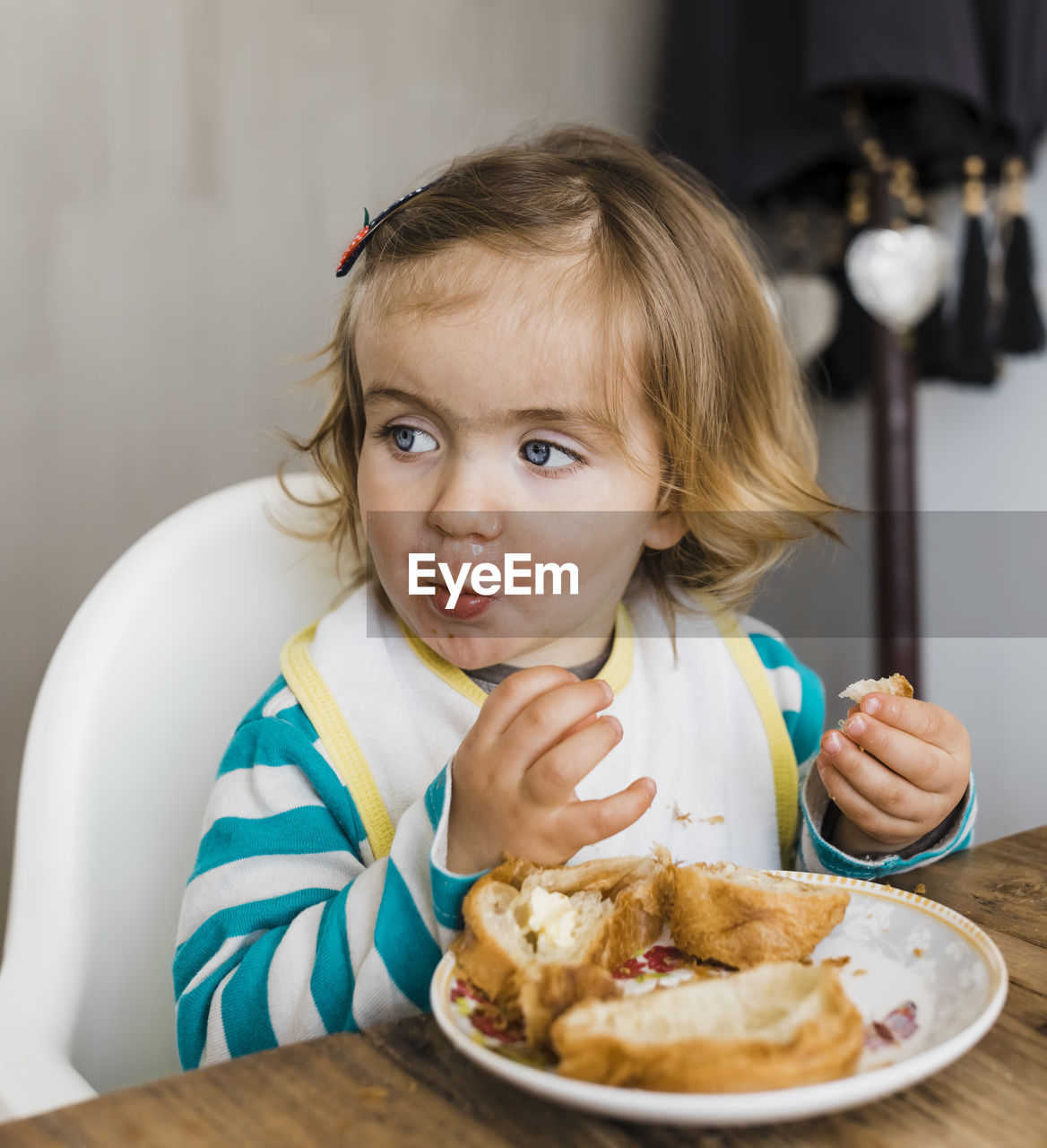 Cute girl looking away while eating food at home