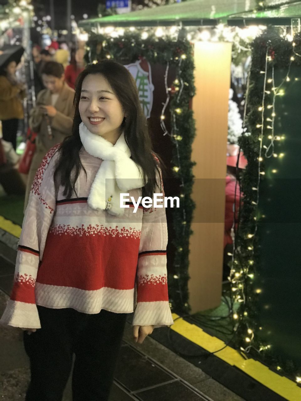 Smiling woman standing outdoors during christmas at night