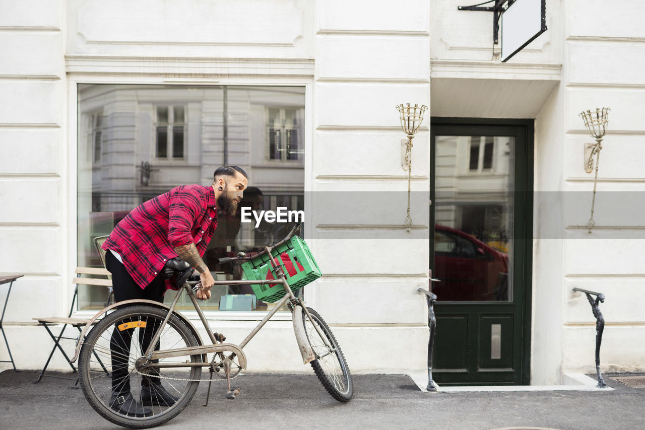 Owner locking bicycle on sidewalk outside candy store