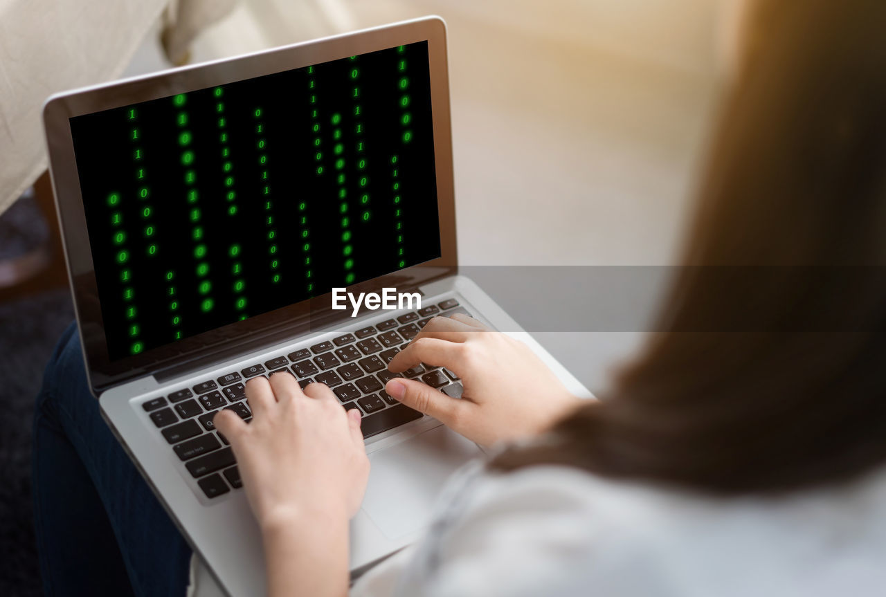 Cropped image of woman using laptop at home