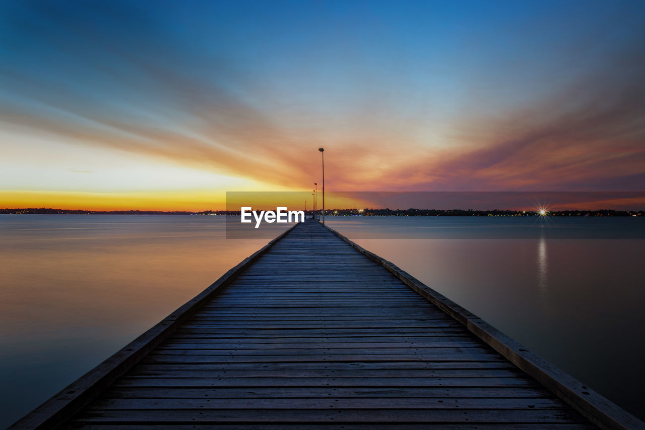 Pier over sea against sky during sunset