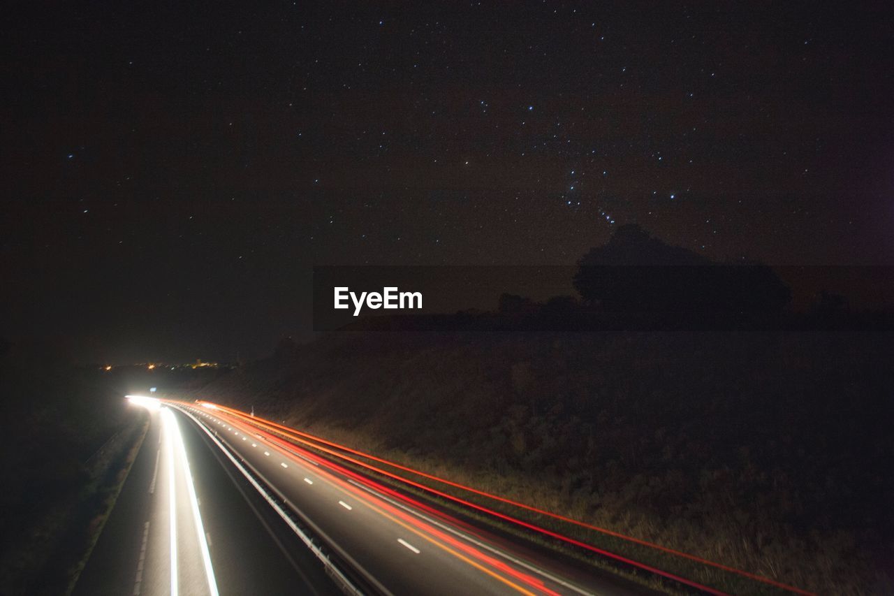 Light trails on road against sky at night